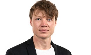 Zu sehen ist eine Portraitaufnahme von Lucas von Ramin vor einem grünen verschwommenen Hintergrund