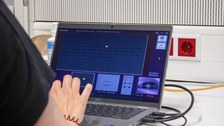 Eine Hand am Laptop, unten rechts ist das Auge der Probandin zu sehen