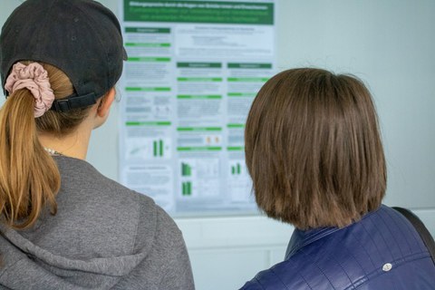 Zwei junge Personen schauen sich ein Poster an