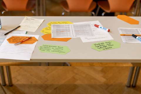 Auf einem Tisch liegen unterschiedlich farbige Blätter und Lernmaterialien.