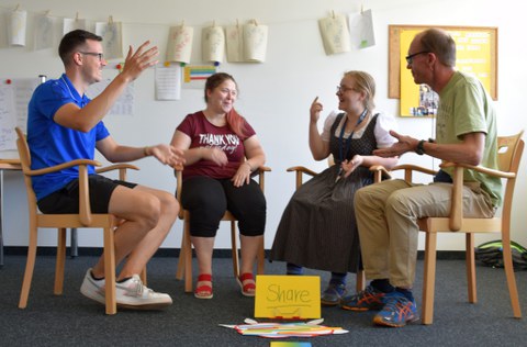 Auf dem Foto sitzen je zwei Männer und Frauen im Halbkreis auf Stühlen und diskutieren.