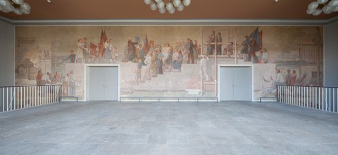 Foto eines Wandgemäldes: Das Gemälde zeigt über die gesamte Wand den Dresden-Besuch des Staatspräsidenten der DDR, Wilhelm Pieck. Er ist umringt von Menschen verschiedenen Alters, teils mit Fahnen, Werkzeugen, Büchern, Blumensträußen.