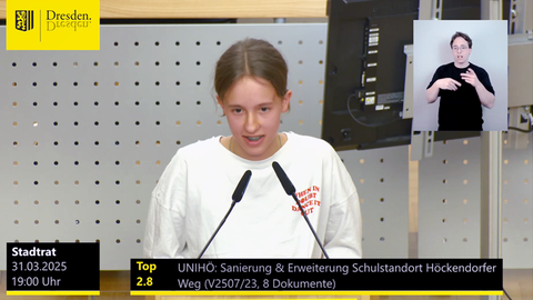 Eine junge Frau spricht am Podium in ein Mikrofon