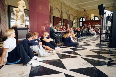 Guests are seated at tables and on the floor at Café Algarotti in the Semper Building.