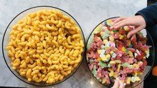 Two large bowls filled with colorful gummy bears and peanut flips. Two children's hands reach for the gummy bears.