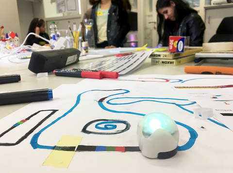 Arbeitstisch in der Medienwerkstatt. Der Minicomputer Ozobot folgt einer Linie auf einem Blatt Papier. 