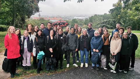 Etwa 30 Personen stehen vor dem regnerischen Panorama des TUD-Campus mit Blick auf den Weberbau.