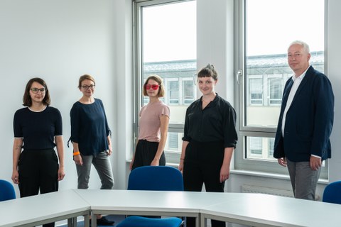 Foto der Mitarbeiterinnen und Mitarbeiter des TP I im Büro, stehend hinter Tischen und vor einem Fenster, 5 Personen
