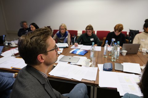 Menschen sitzen in einem Konferenzraum um einen Tisch