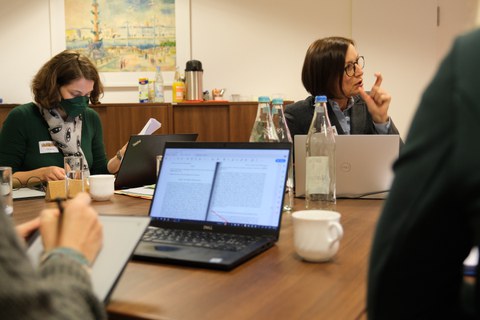 Menschen sitzen in einem Konferenzraum um einen Tisch