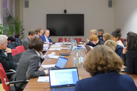 Menschen sitzen in einem Konferenzraum um einen Tisch