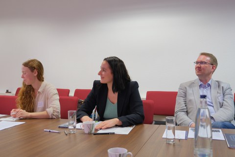 Menschen sitzen an einem Tisch und diskutieren miteinander