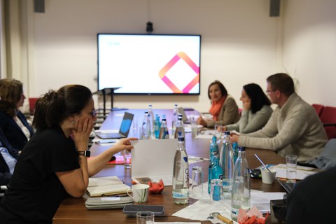Menschen sitzen an einem Tisch und diskutieren miteinander