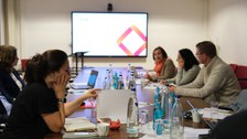 Menschen sitzen an einem Tisch und diskutieren miteinander