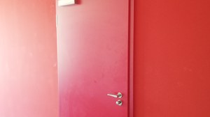 Das Foto zeigt die rote Tür zum LMLab. Über der Tür hängt ein Schild mit der Aufschrift "on air".