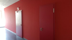 Das Foto zeigt zwei rote Türen in einem rot gestrichenen Flur, die linke stellt die Tür zum LMLab dar.