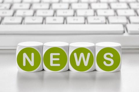 Das Foto zeigt vier Buchstabenwürfel, die zu dem Wort "News" zusammengestellt sind. Im Hintergrund erkennt man eine weiße Computertastatur.