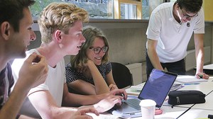 Foto einer Gruppe von Studierenden, die auf den Bildschirm eines Laptops schauen