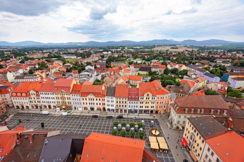 Blick auf das Hauptgebäude des IHI Zittau am Zittauer Markt vom Turm der Johanniskirche. Im Hintergrund ist das Zittauer Gebirge zu erkennen.