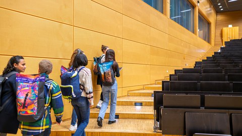  Studierende, wie sie in einem Hörsaal auf dem TUD-Campus eine Treppe hochlaufen.
