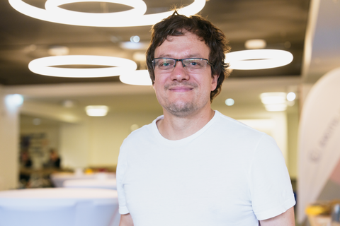 The person Robert Kuschmierz wears a white shirt and glasses. He has brown hair and smiles directly into the camera.