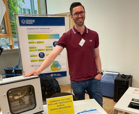 Mann mit technischem Equipment vor einem wissenschaftlichen Poster
