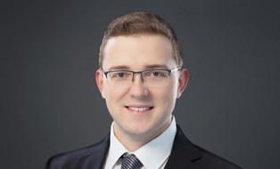 Kurzhaariger Mann mit Brille, gekleidet in Anzug und Krawatte
