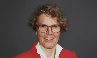 Lächelnde Frau mit Locken und einem roten Blazer