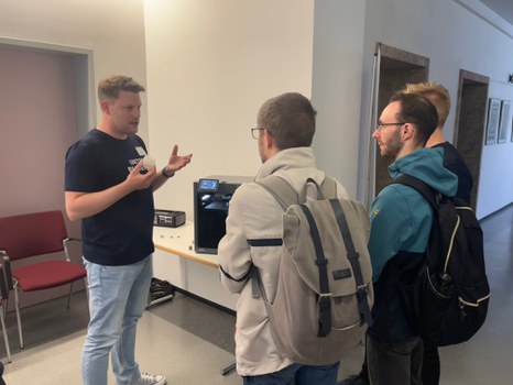 Mitarbeiter erklärt Besuchern den 3 D Druckern