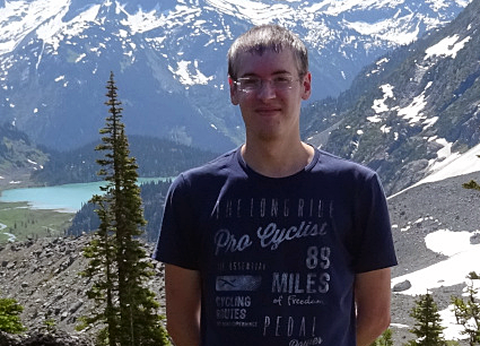 Daniel Neuen auf einer Alm stehen mit Bergen im Hintergrund