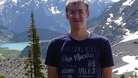 Daniel Neuen auf einer Alm stehen mit Bergen im Hintergrund