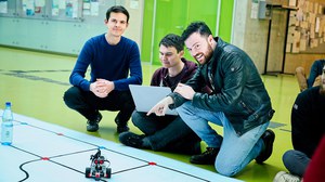 drei Studenten beim RoboLab im Foyer der Fakultät Informatik mit Planet und Legoroboter im Vordergrund
