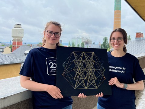 Vorstellung Lange Nacht der Wissenschaften, zwei Personen mit Deko zu Neuronalen Netzen, im Hintergrund der Campus der TU Dresden