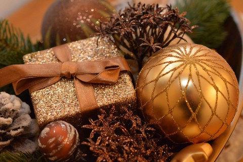 Weihnachtliches Motiv mit goldenem Schein, Geschenke und Weihnachtskugeln, Tannenzapfen und Glitterband.