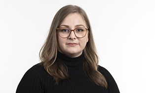 Frau mit langen blonden Haaren, Brille und schwarzem Rollkragenpullover