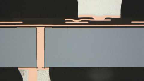 Cross-section of a functionalized LTCC multilayer strucure. The blue ceramic body differs strongly from the orange conducting traces.
