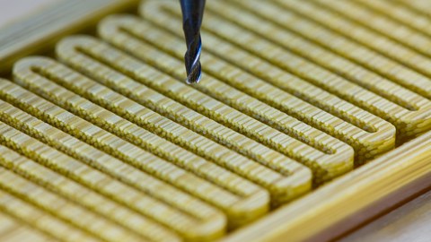 Closed view of a piezoceramic actuator. The device is set up from many ceramic fibres, arranged in a resin matrix, being milled into a in meandering pattern.