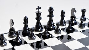 The picture focusses on the black figures of a chess set made of ceramic.