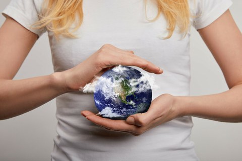 Globe held in the hands in front of a body.