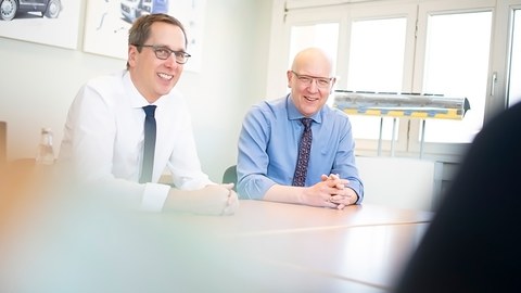 Two men sit at a table laughing.