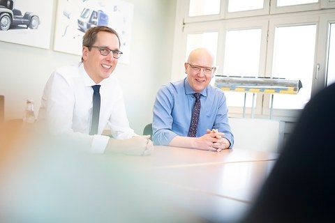Two men sit at a table laughing.