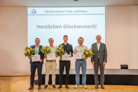 Fünf Männer stehen in einer Reihe und lächeln in die Kamera. Von links nach rechts: Vier Männer mit Blumenstrauß und Urkunde, der rechte Mann lächelnd (Prof. Modler).