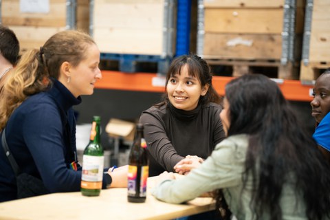 Female students sit at the table and chat animatedly.