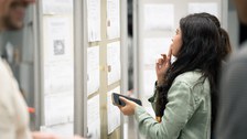 A student stands at a notice board and looks at the job offers with interest.