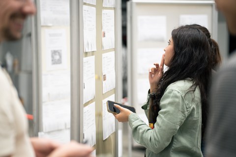 A student stands at a notice board and looks at the job offers with interest.