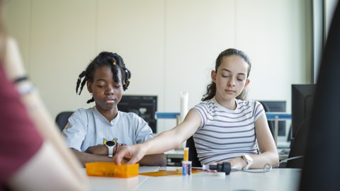 Girls' Day Academy 2025: Girls sit at a table examining plastics.