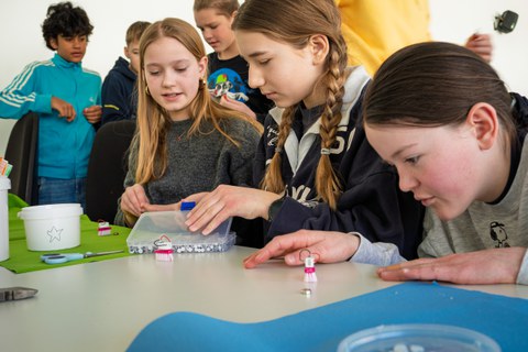 Children are sitting at a table doing arts and crafts.