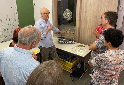 Prof. Modler in conversation with the guests, in the background are fibre-reinforced composite materials.