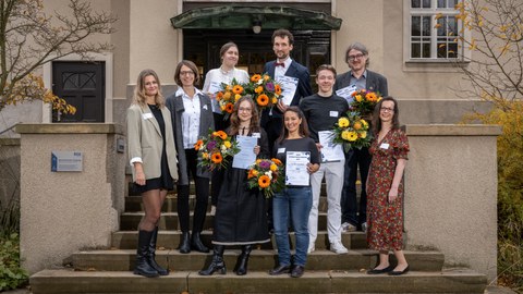 Eine Gruppe von Menschen steht zusammen und hält Urkunden in den Händen.
