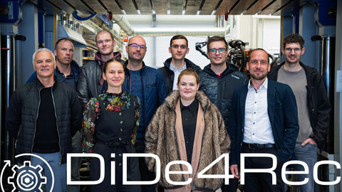 Ten people (eight men, two women) stand in front of a hydraulic press and smile at the camera. The DiDe4Rec logo appears on the photo.